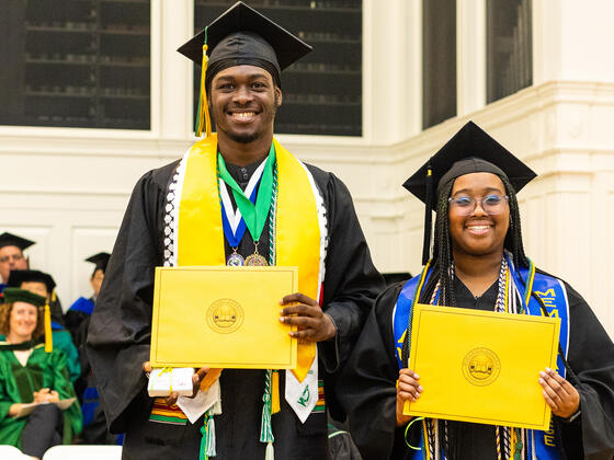 students in graduation regalia pose with awards
