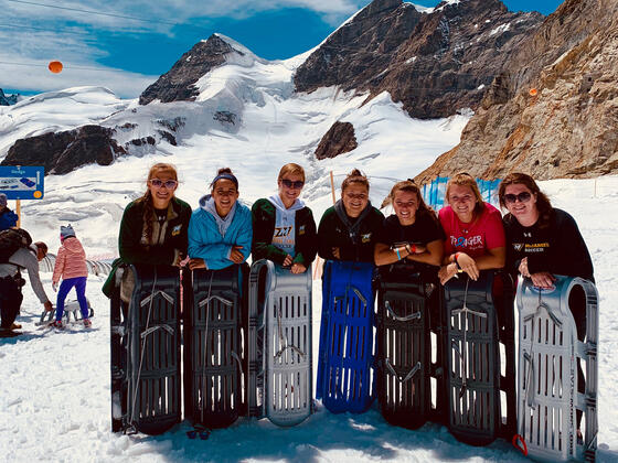 Women's Soccer team in the Alps, standing with sleds.