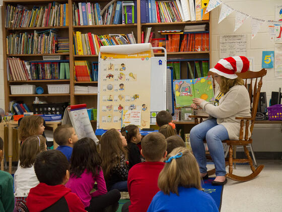 Student reading to a classroom full of elementary school children.