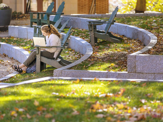 Student sitting in outdoor chair on campus.