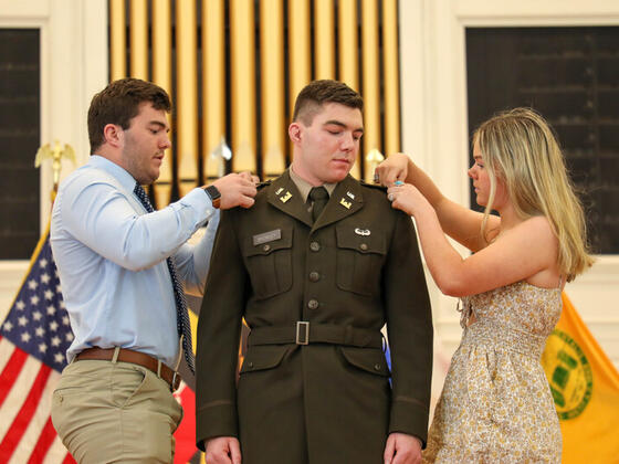 Michael Bromley at Commissioning with family adding pins to his uniform.