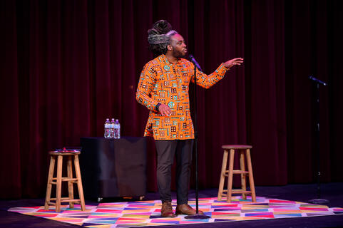 Spoken word poet Adan Bean speaks on a stage.