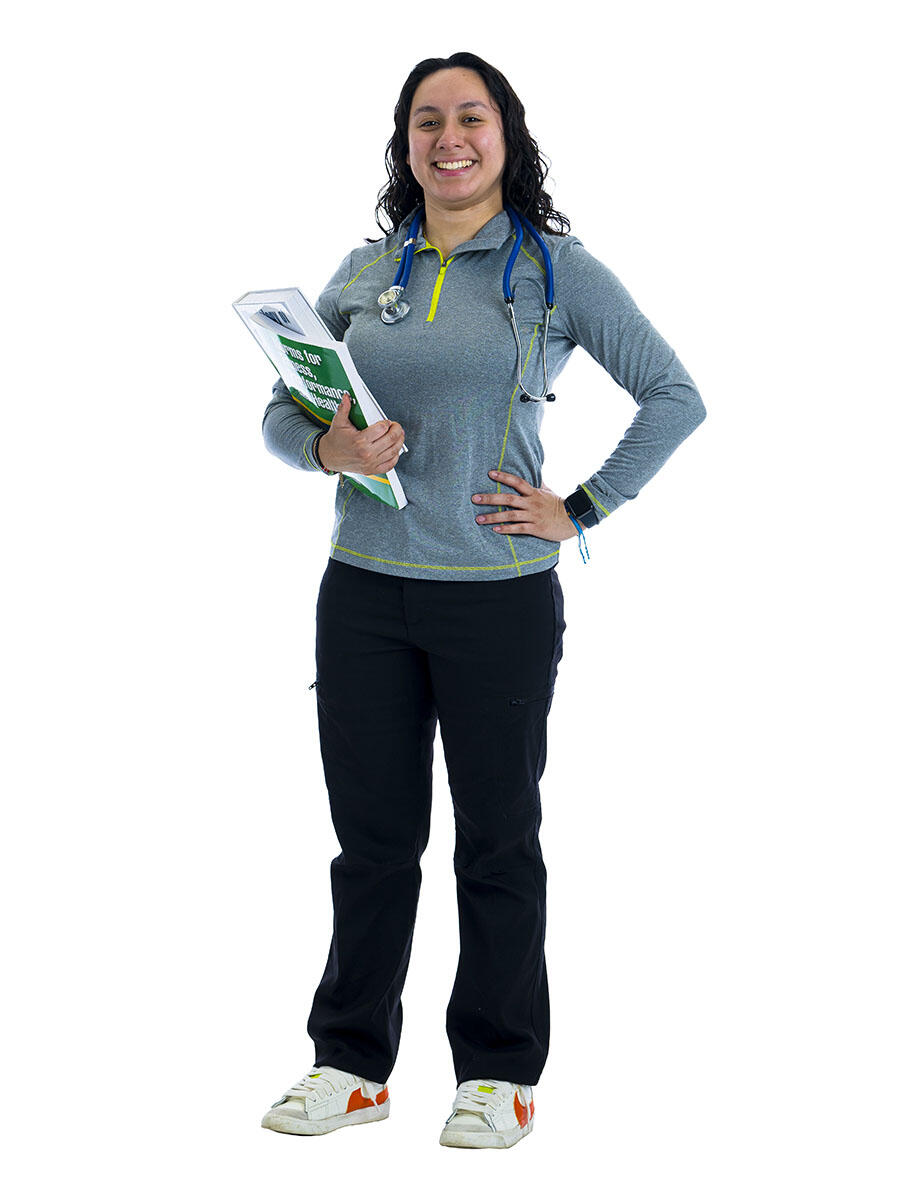 A student with a stethoscope around her neck holds a stack of books in front of a white background.