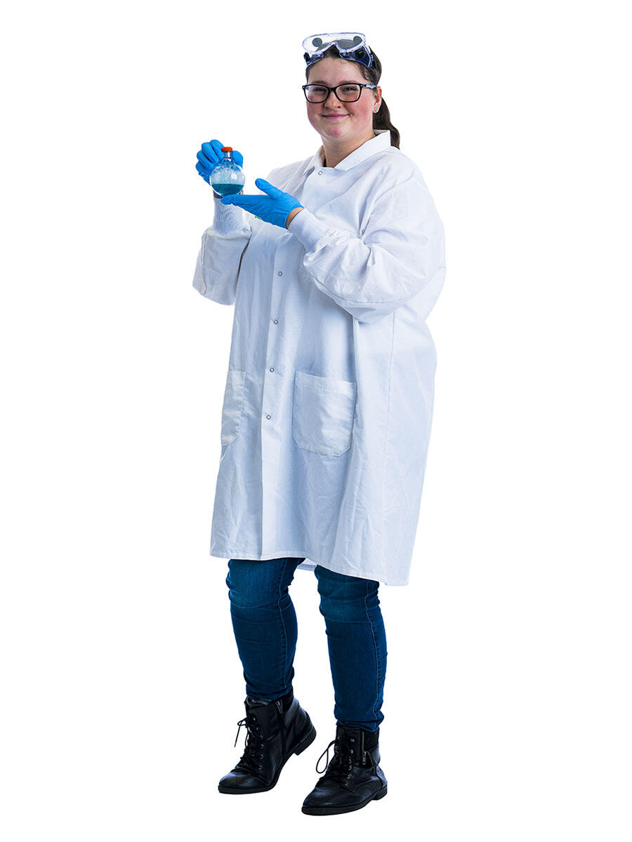 A student in a lab coat stands in front of a white background while wearing a pair of science goggles on their head and blue gloves and holding up a beaker with a blue liquid inside.