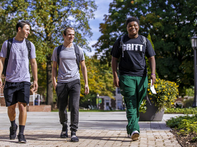 Three students walking together on campus.