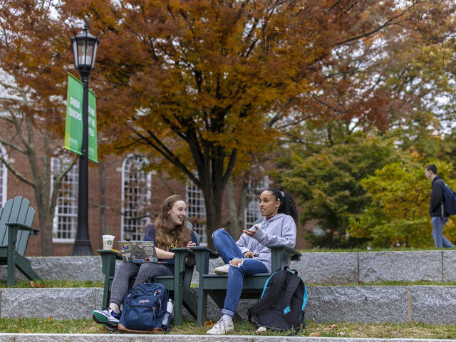 Students sitting in outdoor chairs on campus.