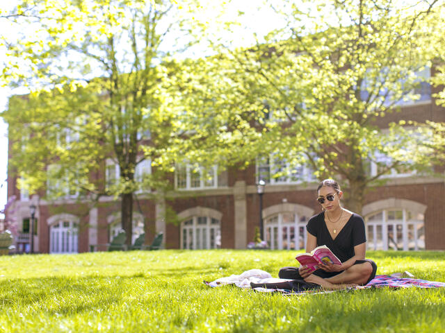 student reading a book in the grass