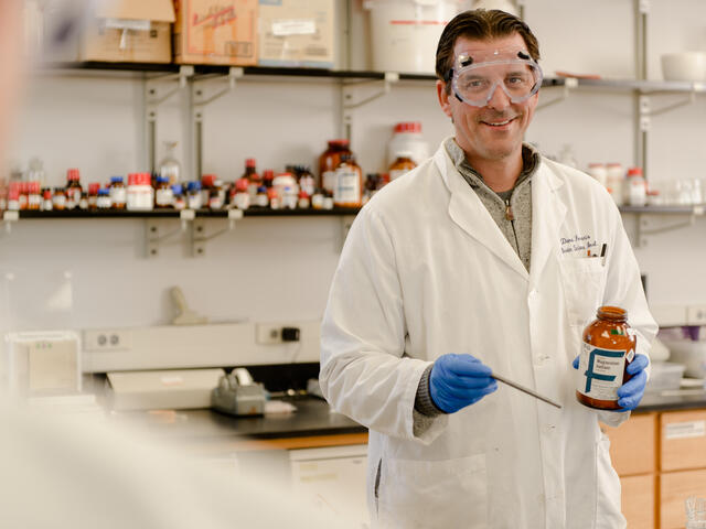 Photo of Chemistry Professor Dana Ferraris in the lab wearing a lab coat and goggles.