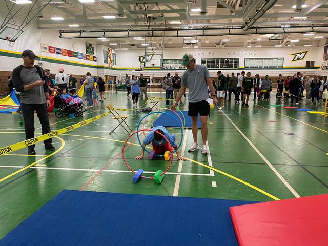 A student helps a child complete the Tournament of Champions obstacle course.