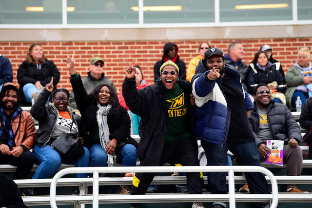 Photo of a group of men and women in the bleachers cheering at McDaniel Homecoming football game.