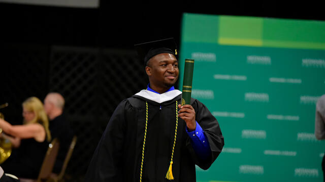 Student with diploma in hand at Commencement 2019.