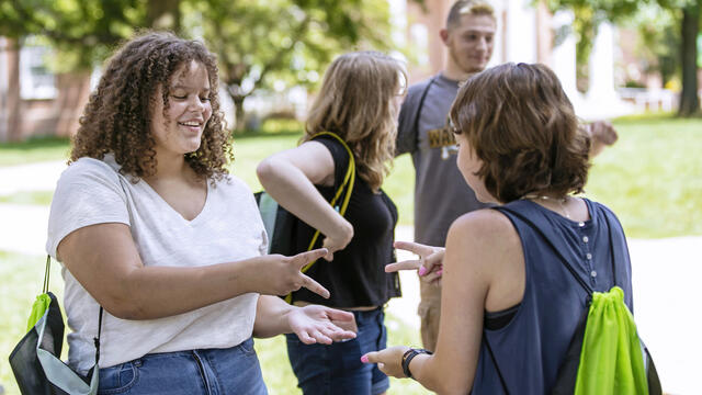 Students playing rock paper scissors on campus.