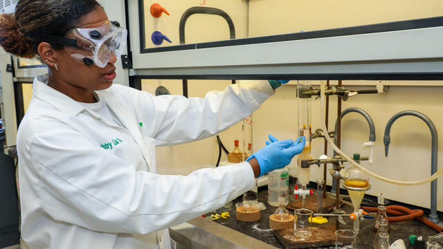 A student demonstrates a chemistry process in the lab.