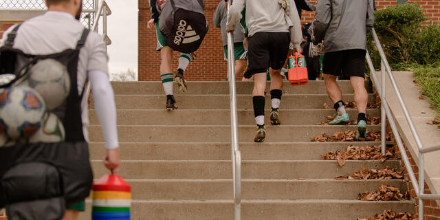 Athletes climbing staircase on campus.