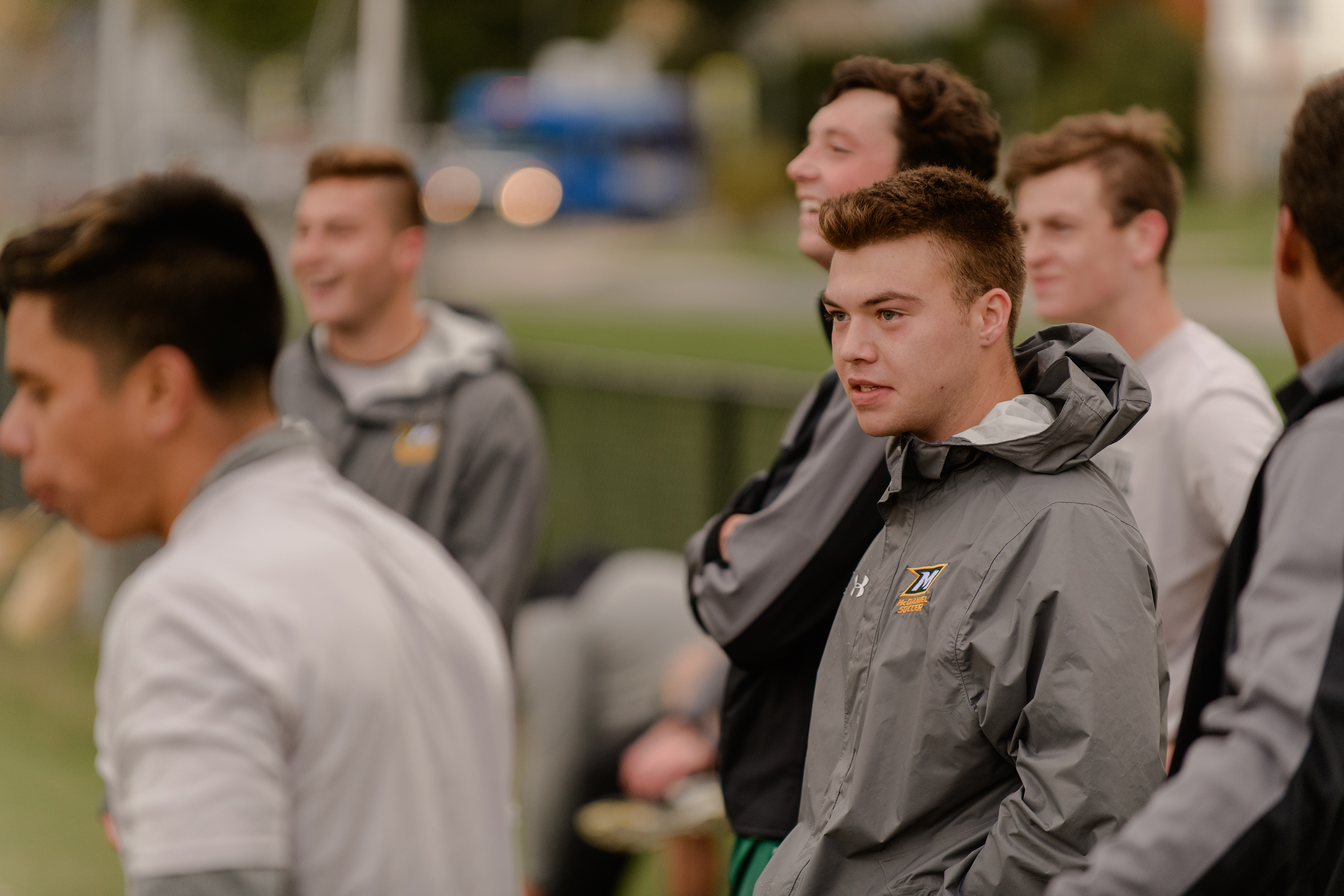 Men's soccer players on the sidelines.