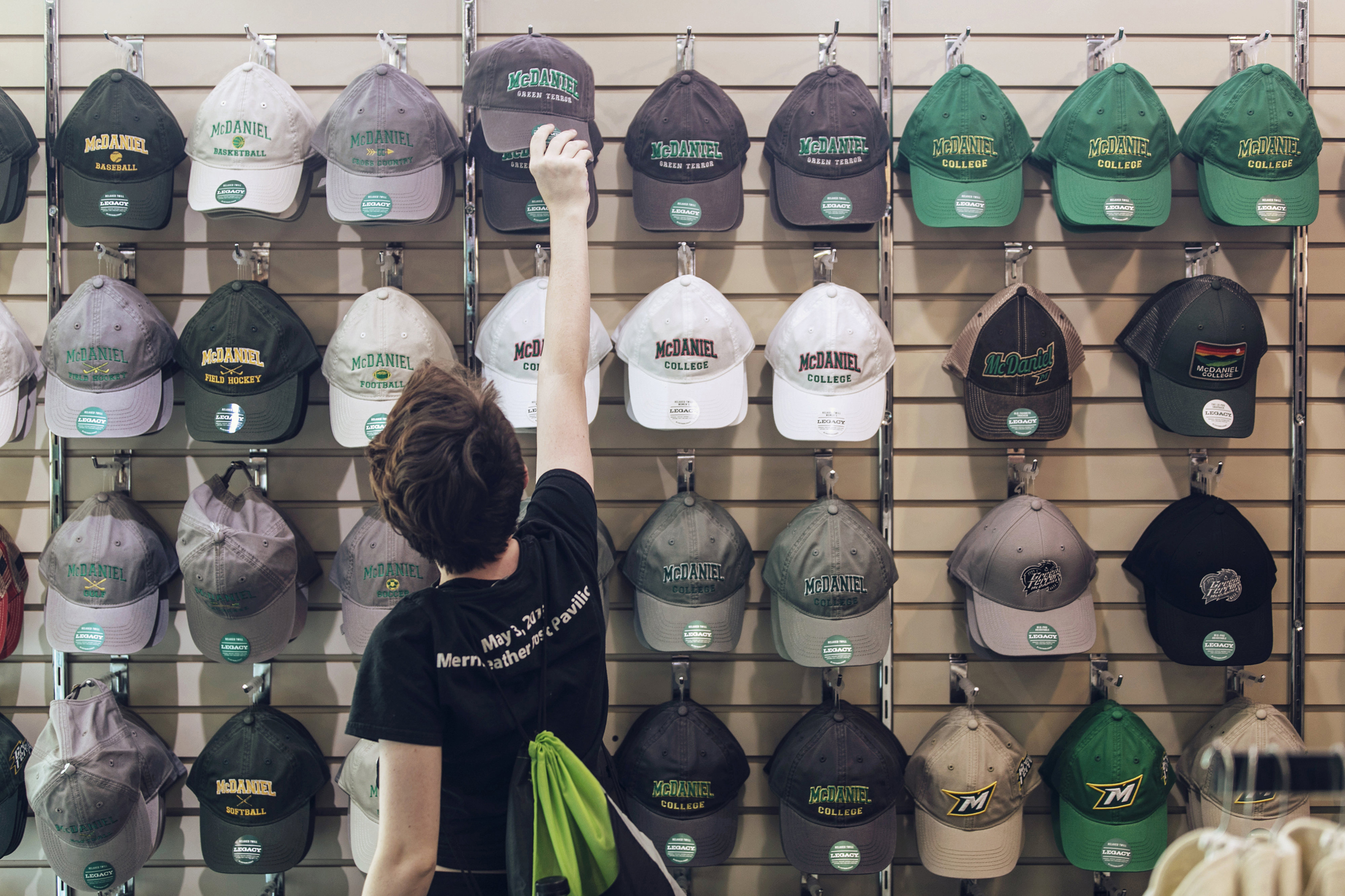 Student selecting McDaniel hat in campus bookstore.