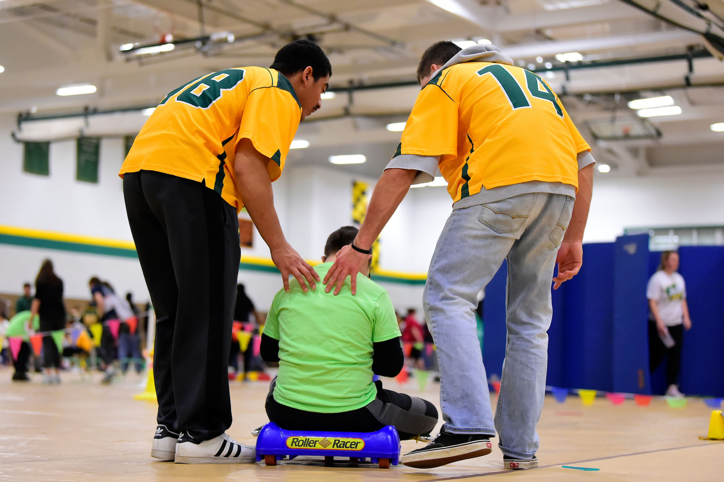 Athletes helping child on scooter at Tournament of Champions