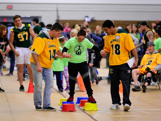 McDaniel students Michael Scott, left, and senior Jared Payne, both lacrosse players, cheer on Tournament of Champions athlete Jason Rivas, a seventh-grader at Montgomery Village Middle School.