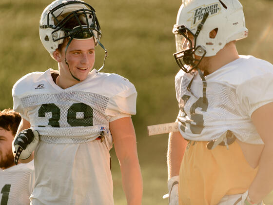 Football players in conversation at practice on the football field.