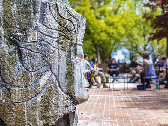 Sculpture outside of Hoover Library with students in background.