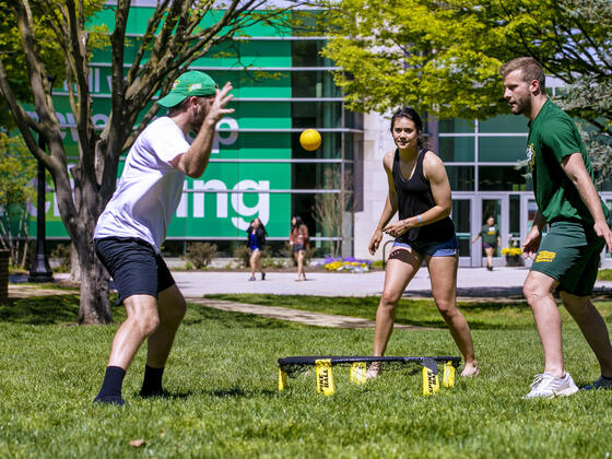 Students playing Spikeball on campus lawn.