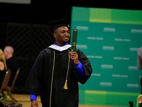 Student with diploma in hand at Commencement 2019.