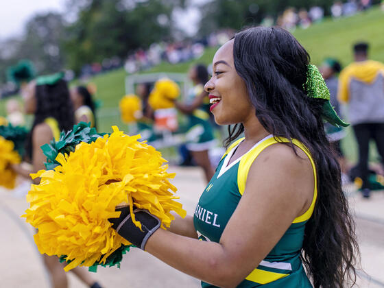 Cheerleader cheering on team at homecoming football game.