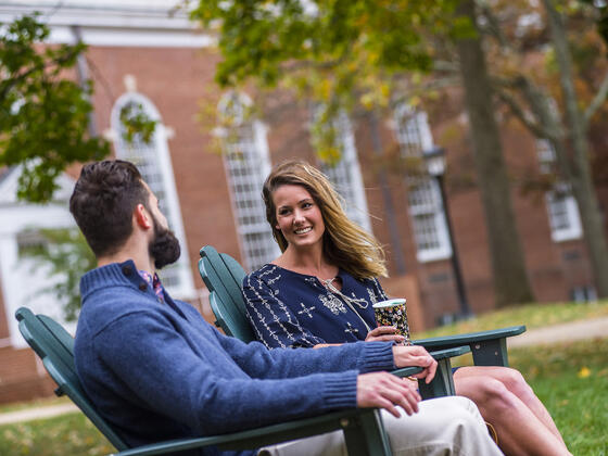 Grad students sitting in outdoor chairs on campus.