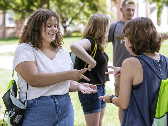 Students playing rock paper scissors on campus.