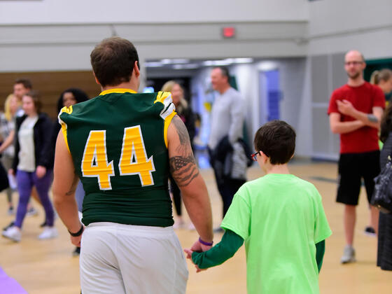 Football player holding child's hand at Tournament of Champions