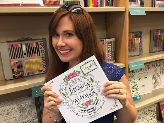 Amy Latta ’02 holding a copy of her book, “Hand Lettering for Relaxation.”