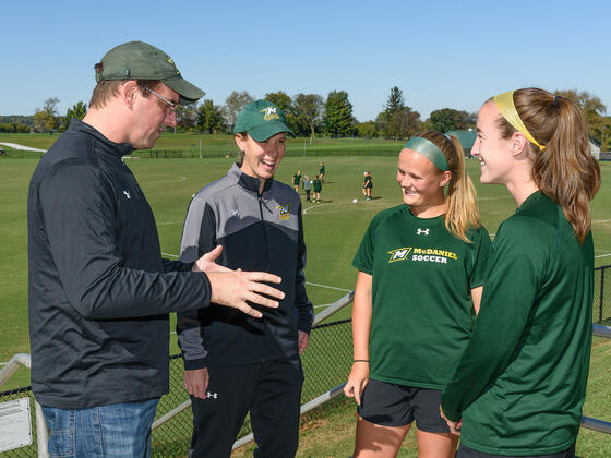 Chemistry professor Dana Ferraris, faculty athletics mentor to the women's soccer team, explains to coach Sandy Lagana and team co-captains Abby Keen and Kristen Upton how he and his wife make the bagels he brings to the team on home-game mornings.