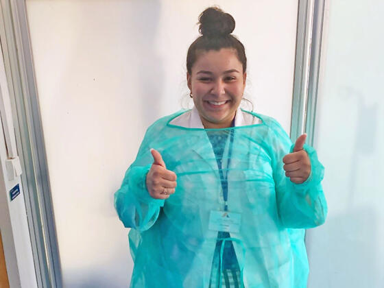 Student in protective gown giving thumbs up.