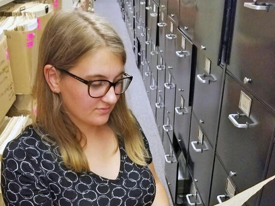 Student pulling out a file from a file cabinet.