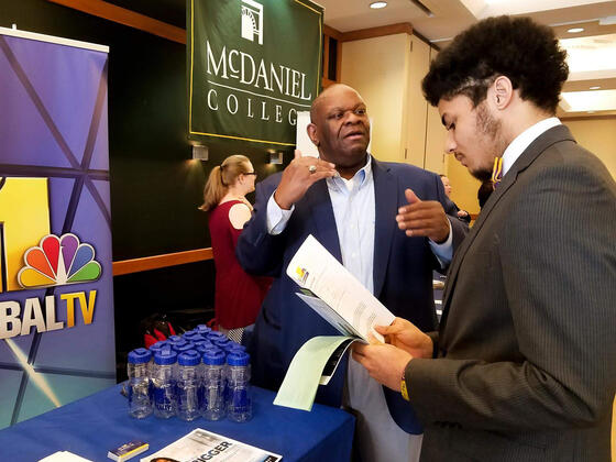 An employer talks to students at a job and internship fair.