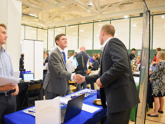 An employer talks to students at a job and internship fair. 