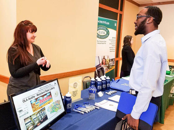 An employer talks to students at a job and internship fair.