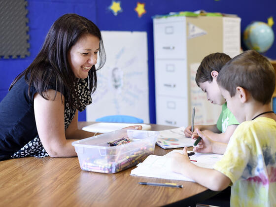 Student interacting at desk with elementary school children.