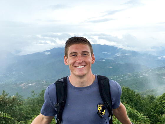 Student in scenic setting with mountains in the background.