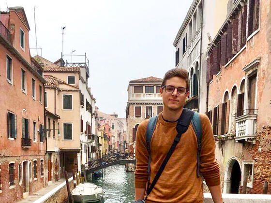 Student standing on bridge over canal.