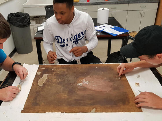 Students work on fitting the inserts and filling in the gaps with canvas fluff to even out the surface before relining.