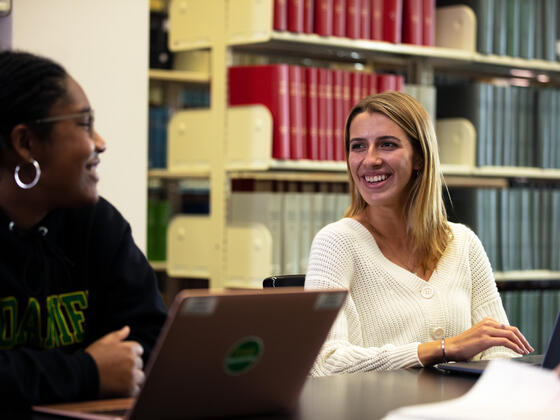 Two students smiling at each other in Hoover Library.