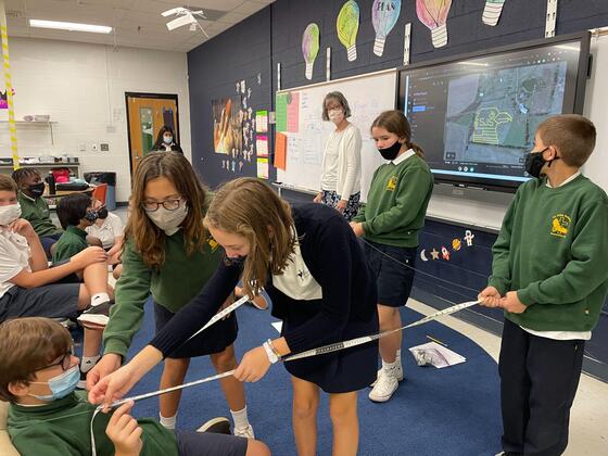 Clare Hoerl in the classroom with her students while they learn to use measuring tapes.