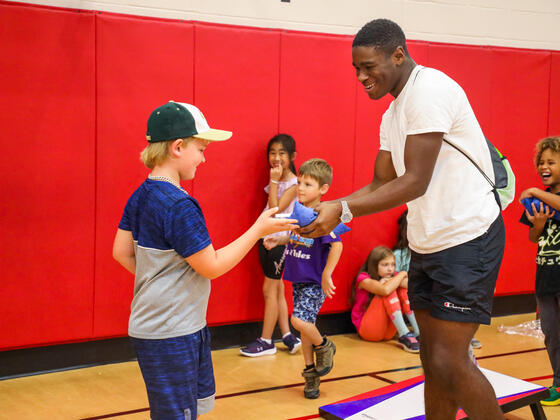 A students hands a child a beanbag at the Boys and Girls Club of Westminster.