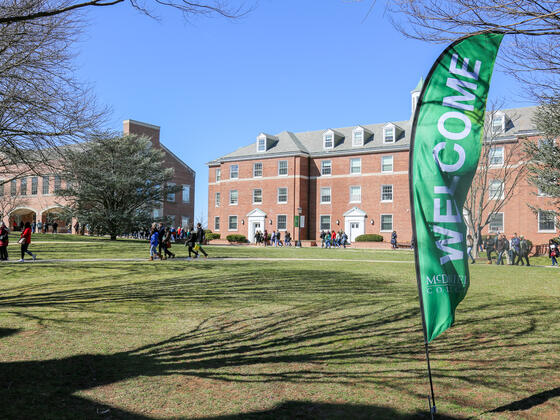 Welcome Flag with campus building and people in background