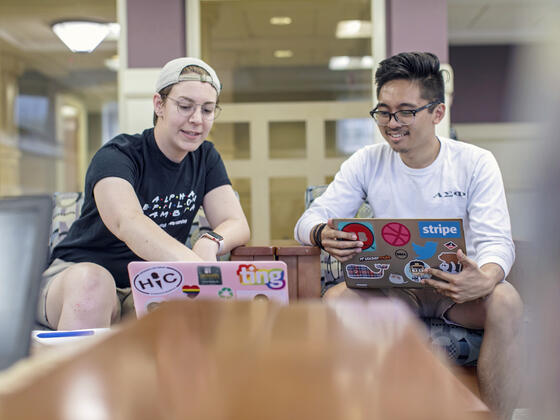 Two student look at a laptop together.