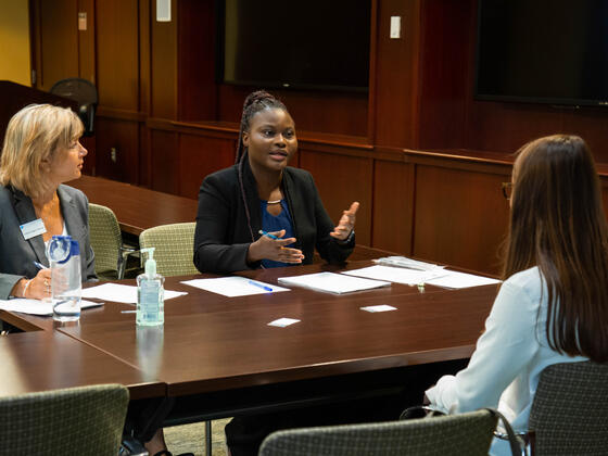 Three people in suits talking at a table.