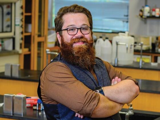 Photo of professor Ben Smith standing in a science lab with arms crossed.