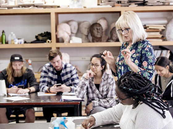 Photo of professor Katya Dovgan speaking with students in the Art Studio.