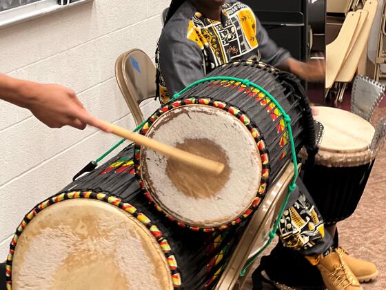 Drum instructor Paco Samb using a djembe while a student plays the dundun.